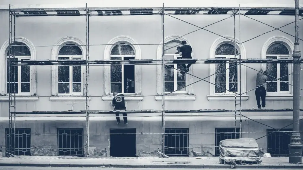 Ouvriers sur un échafaudage rénovant la façade d'un immeuble