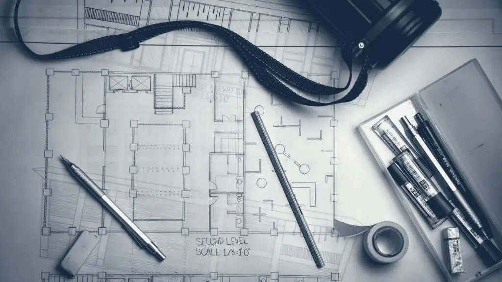 Plans d'architecte, crayons et réglet métallique posés sur une table
