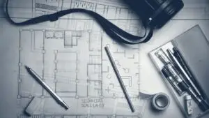 Plans d'architecte, crayons et réglet métallique posés sur une table