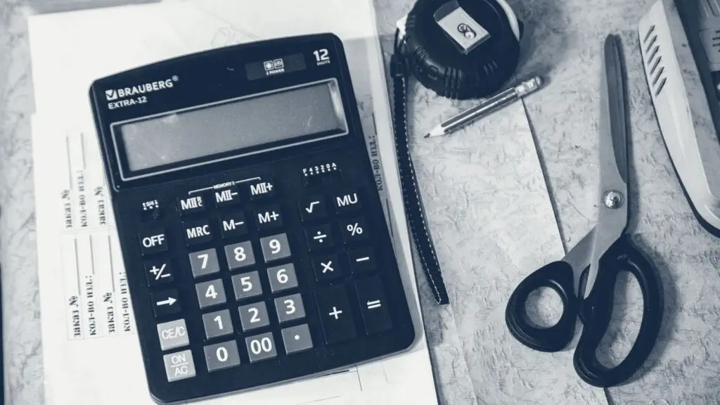 Calculatrice et fournitures de bureau posées sur un plan de travail